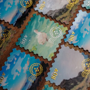 Rows of stamp-like stickers with gold and silver foil elements. Designs include the ocean, a goose in the water & a grassy field
