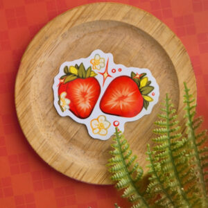 Vinyl sticker of a strawberry cut in half with flowers and sparkles.