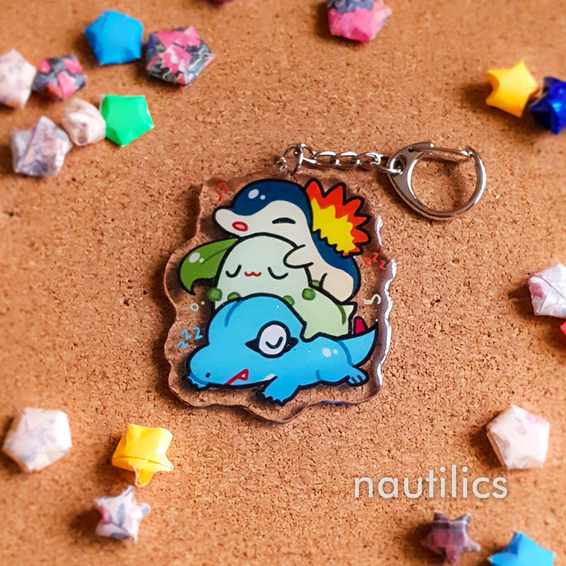 Pokemon Starters Acrylic Charms (B-Grade) by Nautilics Photo of an acrylic charm featuring the Johto Pokemon starters, stacked atop each other in a pile.