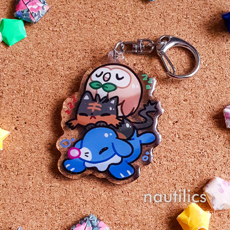 Pokemon Starters Acrylic Charms (B-Grade) by Nautilics Photo of an acrylic charm featuring the Alolan Pokemon starters, stacked atop each other in a pile.