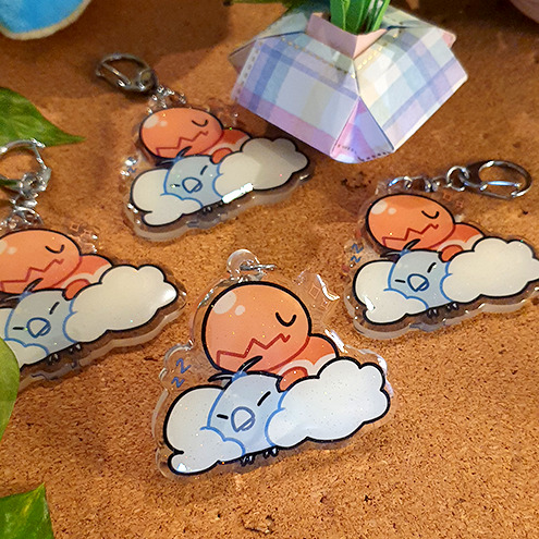 Pokemon Starters Acrylic Charms (B-Grade) by Nautilics Photo of an acrylic charm featuring the the Pokemon Trapinch and Swablu, stacked atop each other in a pile.