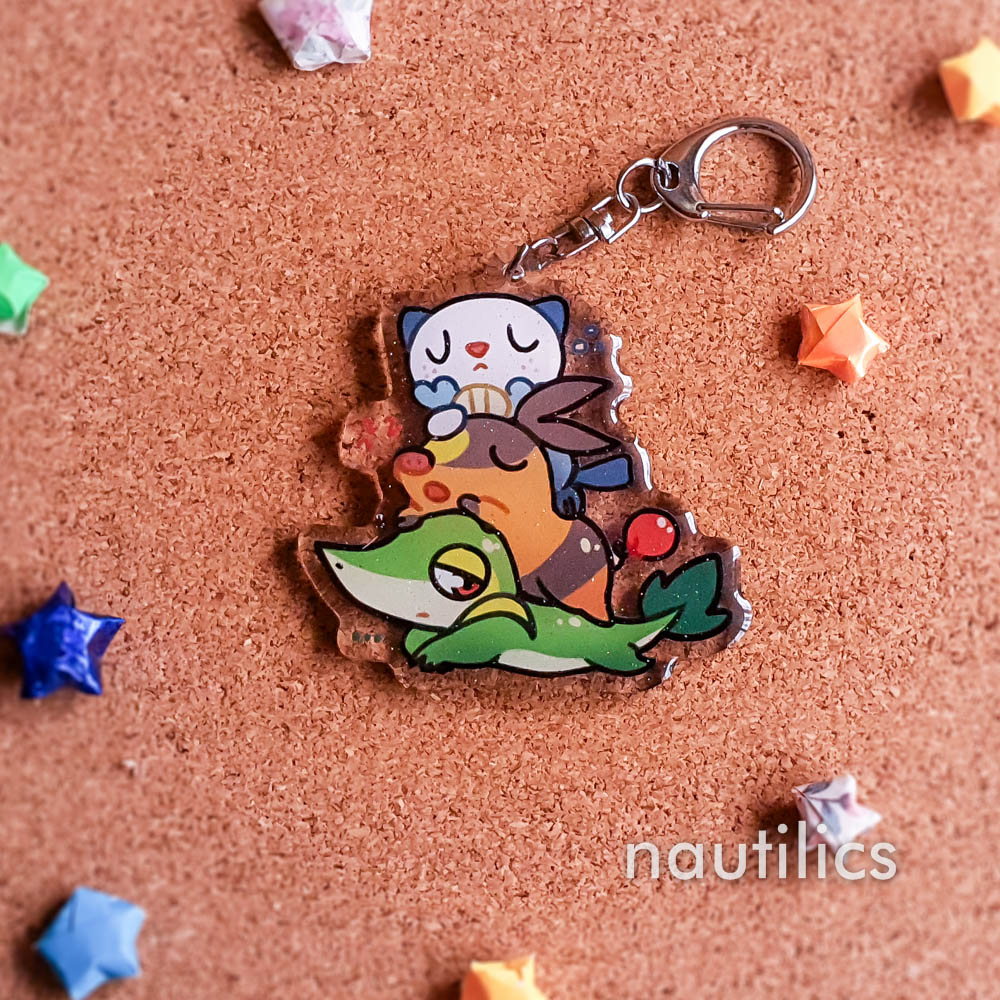 Pokemon Starters Acrylic Charms (B-Grade) by Nautilics Photo of an acrylic charm featuring the Unova Pokemon starters, stacked atop each other in a pile.
