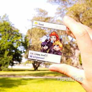 Photo of an instagram-style Kingdom Hearts acrylic keyring, featuring Roxas, Axel, and Xion. The charm is styled so that the characters are at a corner of the frame, so that the background of a green sunny day is visible through the charm behind them.