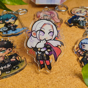 Photo of acrylic charms of characters from Fire Emblem: Three Houses. The main focus of this photo is Edelgard majestically holding a small cat, but other characters are visible in the background.