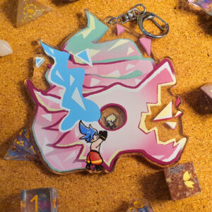 Photo of a large acrylic shaker charm, featuring the dragon from Promare with its crying tears. It includes a tiny Galo at its base, reaching out to the dragon's eye where a tiny Lio can be seen looking back at him.